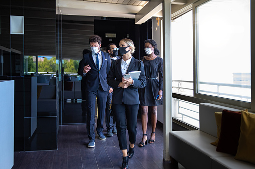 Business colleagues entering the office wearing protective face masks